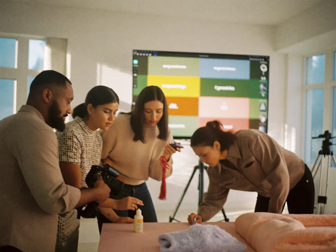 A creative team shooting a skincare product, with many ad versions on a screen behind them