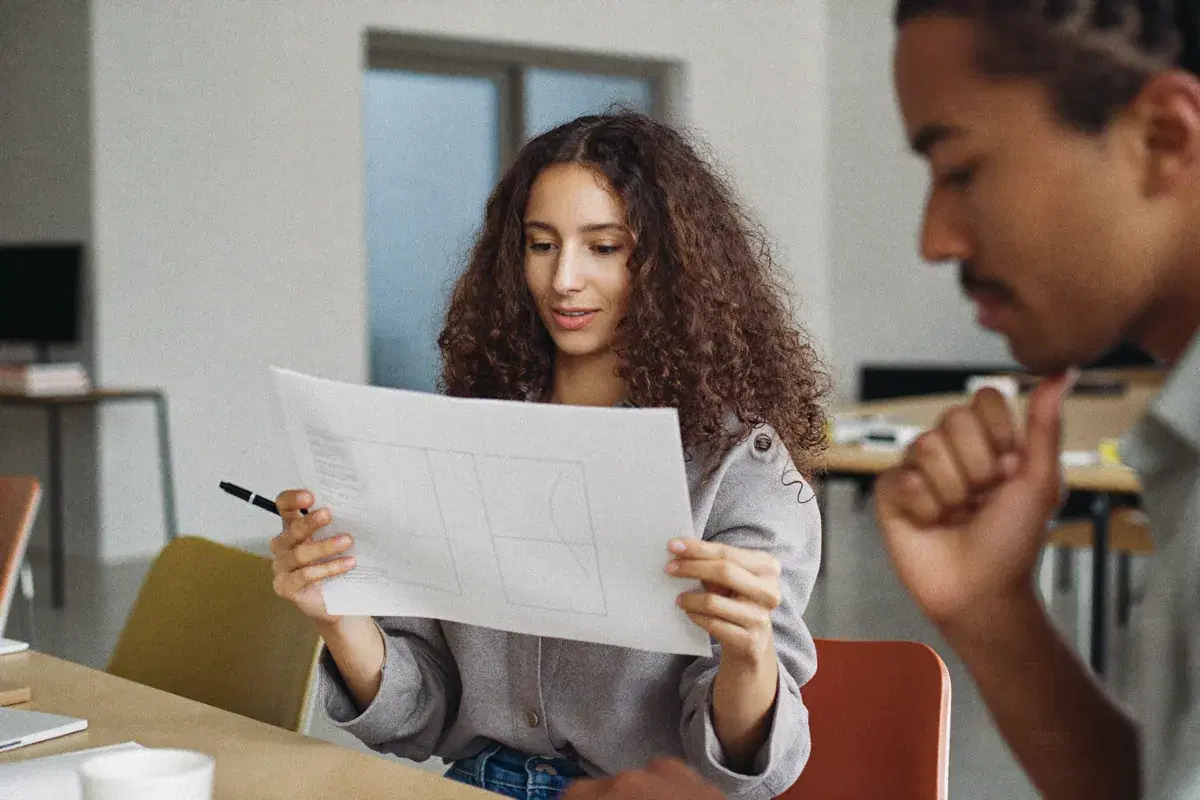 A marketing lead reading a one-page report with a colleague